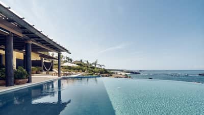 View over infinity swimming pool looking over ocean, covered patio at side